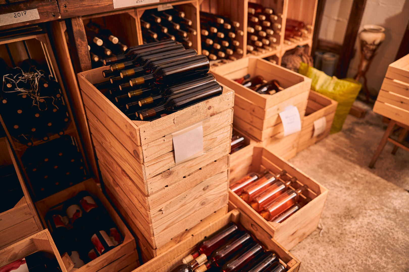 Wine cellar with glass bottles of alcoholic drink in wooden boxes and wine racks with vintage year labels
